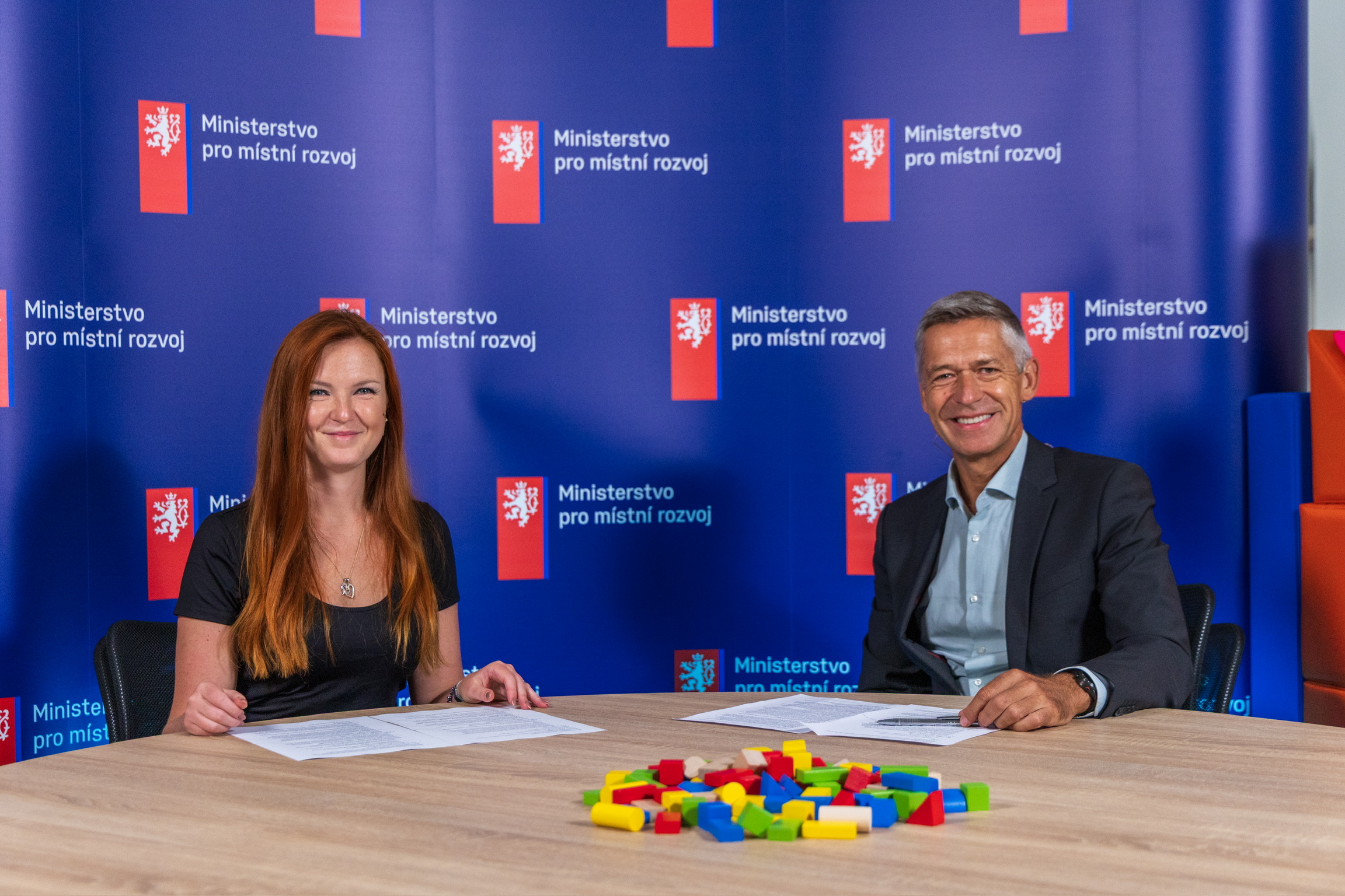 Náměstek Pavel Kryštof a tisková mluvčí Veronika Lukášová sedící před modrým pozadím.